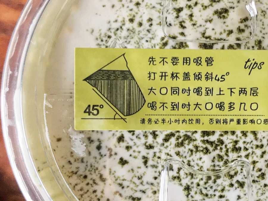 Tips indicated on the lid of cheese tea: don’t drink with a straw at first; tilt the cup at a 45 degree angle; drink mouthfuls of both layers